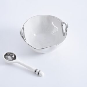 A white bowl and spoon on top of a table.